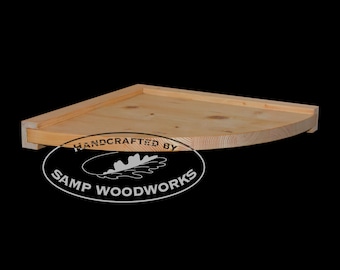 May include: A natural wood corner shelf with rounded edges. The shelf is handcrafted by Samp Woodworks.
