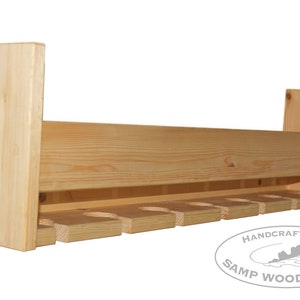 May include: A wooden wine rack with a natural finish and eight slots for holding wine bottles. The rack is handcrafted by Samp Woodworks.