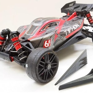 May include: A black and red remote control car with the word "TYPHON" printed on the side. The car has large black wheels, red suspension springs, and a rear spoiler. Additional black aerodynamic parts are included.