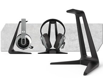 May include: Three black headphone stands with a modern design. Two stands hold silver and black headphones. The third stand is empty. The background is a light gray rectangular shape.