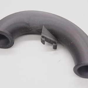May include: A curved, dark gray plastic pipe with two circular openings and a small, attached bracket. The pipe has a textured surface and appears to be a component of a larger system.