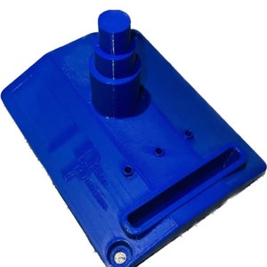 May include: A vibrant blue 3D-printed object, featuring a rectangular base with a raised, cylindrical structure and a rectangular opening. The design includes three small circular holes and a small, circular indentation. The object is likely a tool or component.