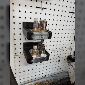 May include: Two metal fittings with various components are mounted on a white pegboard. The fittings are held in black brackets. The top fitting has the number "45" written on it. The bottom fitting has the number ".32kp" written on it.