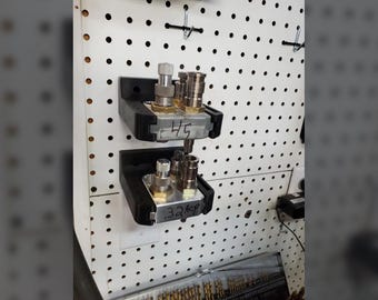 May include: Two metal fittings with various components are mounted on a white pegboard. The fittings are held in black brackets. The top fitting has the number "45" written on it. The bottom fitting has the number ".32kp" written on it.