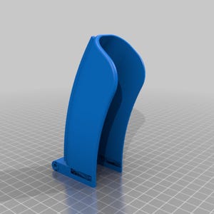 Puede incluir: Objeto azul brillante renderizado en 3D con un diseño curvo en forma de U. Tiene una base plana con una pequeña característica circular en un lado. El fondo es una cuadrícula gris claro.