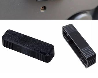 May include: Black rectangular plastic part with a textured surface, possibly a car door handle component. The part is shown in different views, including one installed and two separate pieces.
