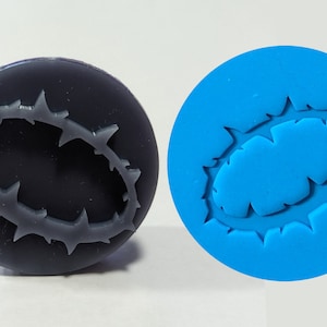 May include: Two round silicone moulds, one black and one blue, with a raised design of a crown of thorns.
