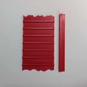 Puede incluir: Dos piezas de plástico rojo, una con un borde ondulado y múltiples líneas horizontales, la otra una pieza recta.