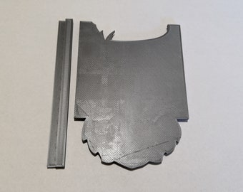 May include: A grey 3D printed model of a card with a decorative design. The card is made up of two pieces, one with a rectangular shape and the other with a more complex shape.