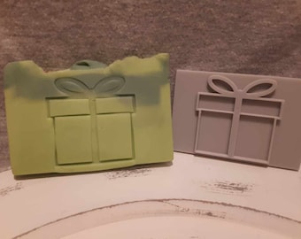 May include: Two gift box shaped silicone molds. One is green and the other is gray.