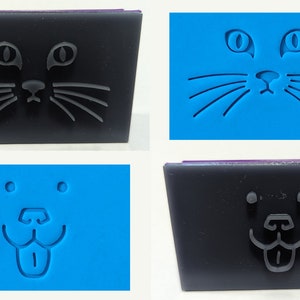 May include: Four silicone molds, two black and two blue, with raised designs of a cat and dog face. The cat face has eyes, a nose, and whiskers. The dog face has eyes, a nose, and a tongue sticking out.