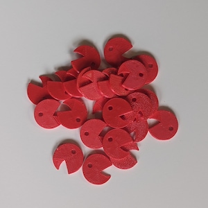 Peut inclure: Un tas de pions de jeu en plastique rouge en forme de Pac-Man. Chaque pièce a un petit trou au centre.