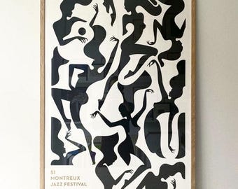 May include: A framed art print featuring a black and white abstract design of silhouetted figures in various poses. The print includes the text "51 Montreux Jazz Festival" and is encased in a light brown wooden frame.