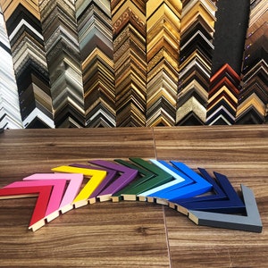 May include: A variety of colorful picture frames arranged in a rainbow pattern. The frames are all in the shape of a chevron and are made of wood.