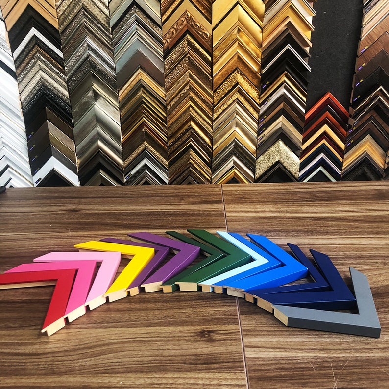 May include: A variety of colorful picture frames arranged in a rainbow pattern. The frames are all in the shape of a chevron and are made of wood.