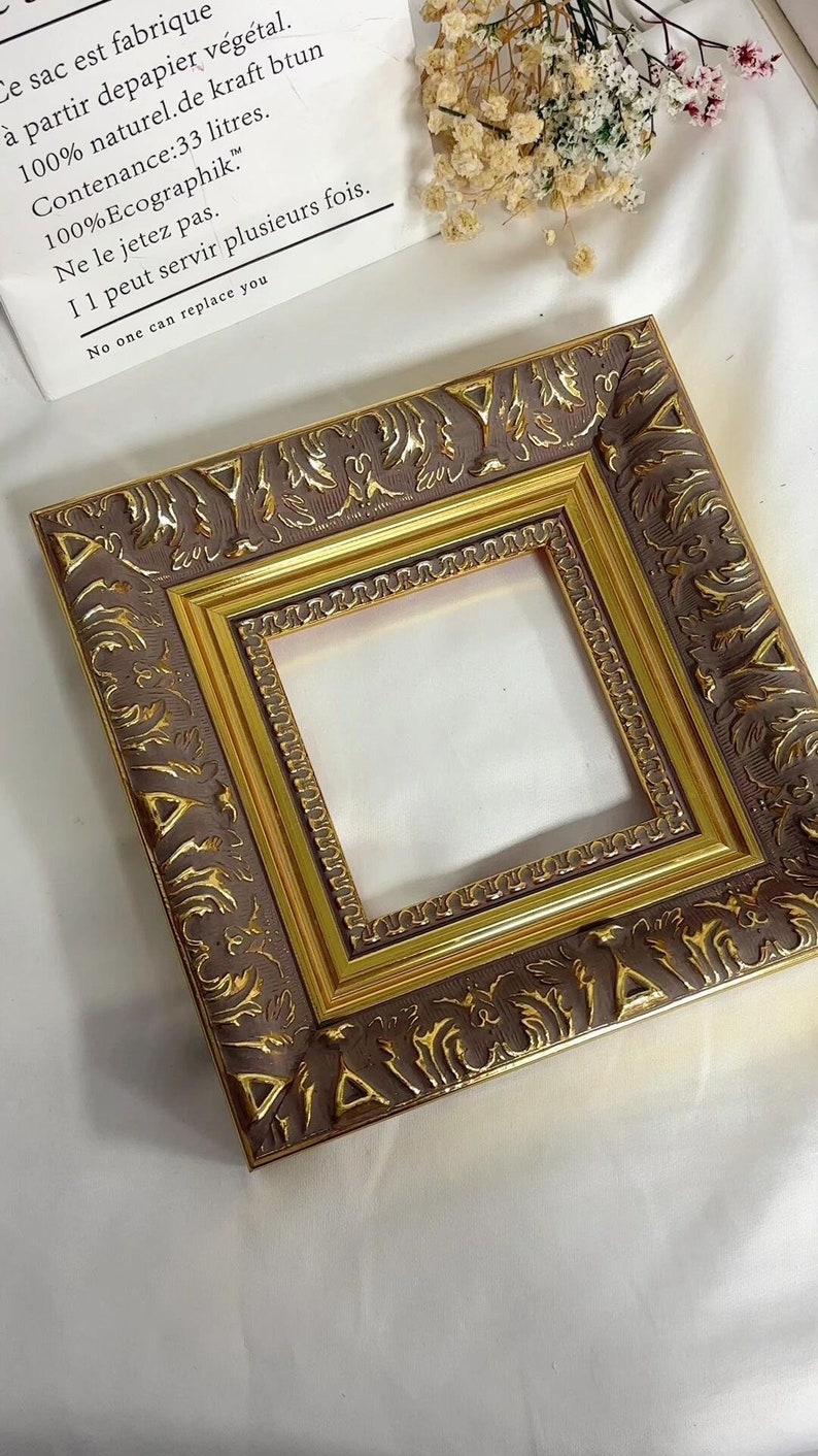 May include: A gold and brown ornate picture frame with a decorative design. The frame is empty and ready to display a photo or artwork.
