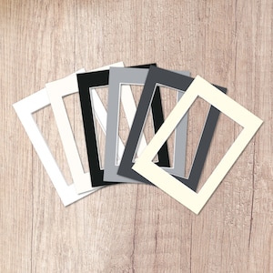 May include: A set of six white, black and grey mount boards with a rectangular opening in the centre. The mount boards are arranged in a fan shape.