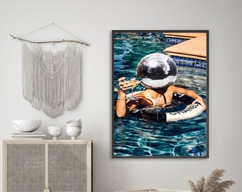 May include: A woman wearing a silver disco ball as a hat floats in a pool with a glass of champagne in one hand and a Chanel life preserver in the other.