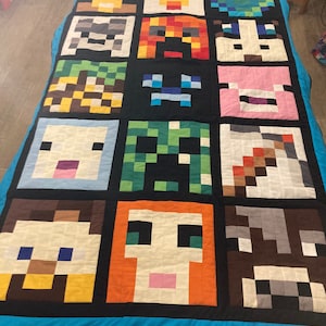 May include: A blue and black quilt featuring a variety of Minecraft character faces in pixelated form. The characters include Steve, Alex, Creeper, Enderman, Pig, and more.