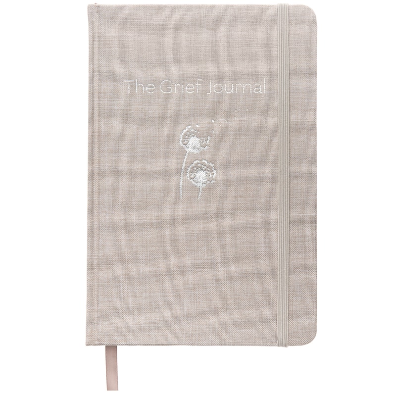 May include: A beige linen-covered journal with the text "The Grief Journal" and a white embroidered dandelion design.