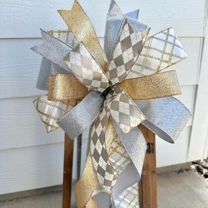 May include: A silver and gold bow with a checkered pattern, perfect for decorating a lantern or other holiday decor.