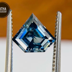 May include: A blue gemstone with a square shape and a slightly pointed top. The gemstone is held in place by a pair of tweezers.