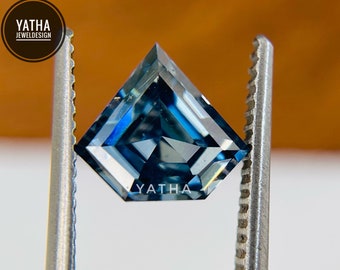 Könnte beinhalten: Ein blauer Edelstein mit quadratischer Form und leicht spitzer Oberseite. Der Edelstein wird von einer Pinzette gehalten.