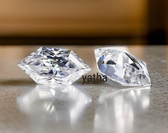 May include: Two clear, faceted, square-shaped gemstones with a slightly rounded edge. The gemstones are on a light grey surface.