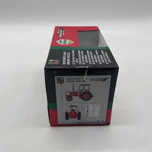 May include: A boxed toy tractor, featuring a weathered David Brown model. The box is red, black, and green, with illustrations of the tractor and the text "WEATHERED DAVID BROWN TRACTOR". The tractor is red and brown.