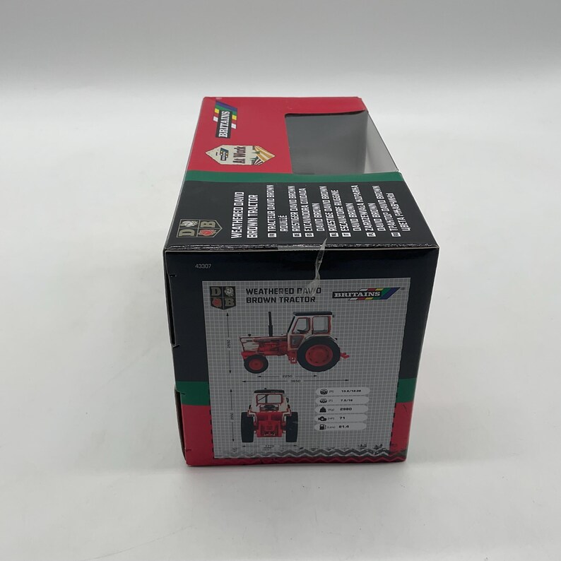 May include: A boxed toy tractor, featuring a weathered David Brown model. The box is red, black, and green, with illustrations of the tractor and the text "WEATHERED DAVID BROWN TRACTOR". The tractor is red and brown.