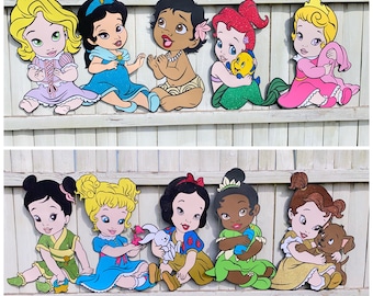 May include: A set of ten Disney princess baby figures. The figures are made of wood and are painted in bright colors. The princesses include Snow White, Cinderella, Ariel, Belle, Jasmine, Mulan, Pocahontas, Tiana, Rapunzel, and Merida.
