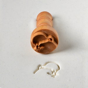 May include: A wooden stamp with a kiwi bird design. The stamp is used to create an imprint of the kiwi bird in clay or dough.