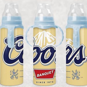 May include: Three baby bottles with a yellow and blue design. The bottles have a blue nipple and a blue ring around the top. The bottles have the word "Coors" in a navy blue script. The bottles also have the words "Banquet Since 1873".
