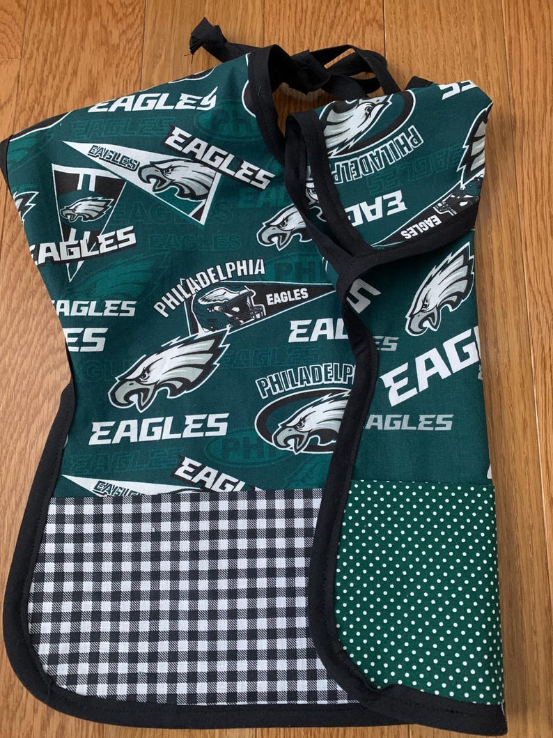May include: Green and black fabric bib with a checkered pattern and a green fabric with white polka dots. The fabric features the Philadelphia Eagles logo and the words "Philadelphia Eagles".