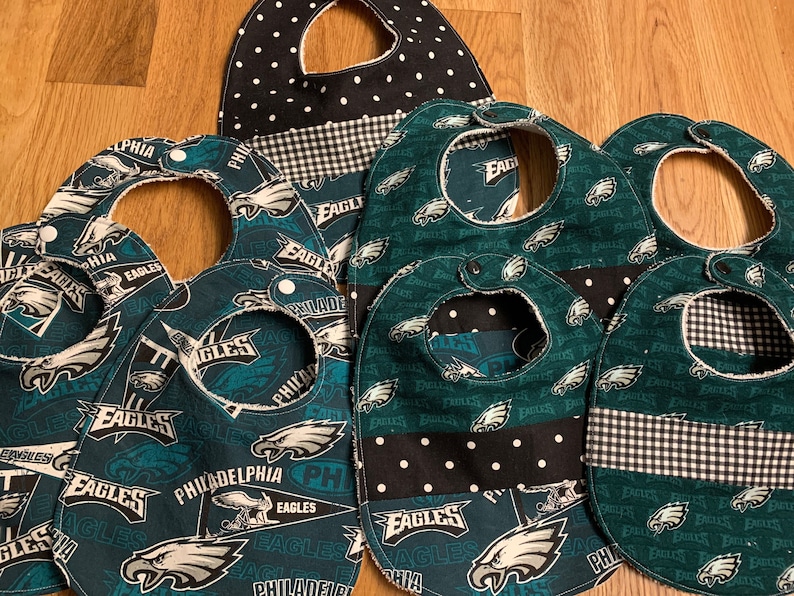 May include: Set of six green and black baby bibs with a Philadelphia Eagles theme. The bibs feature a variety of designs including the team logo, the team name, and the city name.