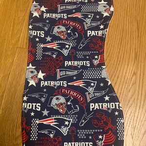 May include: A blue fabric with a white border featuring a repeated pattern of red, white, and blue American football helmets, stars, and the words "Patriots" and "Go Pats!"