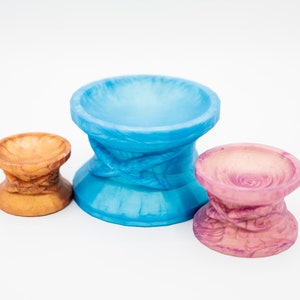May include: Three ceramic pedestals in different sizes and colors. The largest pedestal is blue, the middle pedestal is brown, and the smallest pedestal is pink.