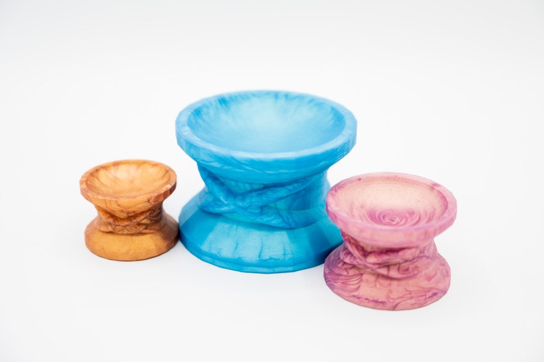 May include: Three ceramic pedestals in different sizes and colors. The largest pedestal is blue, the middle pedestal is brown, and the smallest pedestal is pink.