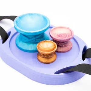 May include: A purple tray with two black straps, holding three small bowls. One bowl is blue, one is pink, and one is brown.
