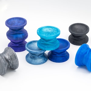 May include: A set of six colorful, swirling, ceramic cups. The cups are in shades of blue, gray, and black. They are all the same size and shape, and they are arranged in a group on a white surface.