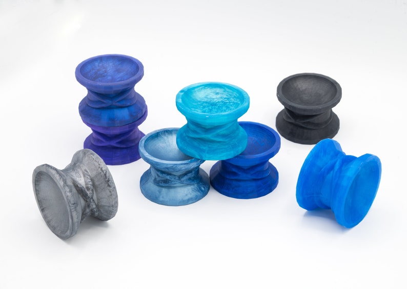 May include: A set of six colorful, swirling, ceramic cups. The cups are in shades of blue, gray, and black. They are all the same size and shape, and they are arranged in a group on a white surface.