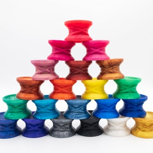 May include: A stack of colorful, double-ended, hourglass-shaped cups, arranged in a pyramid shape. The cups are made of plastic and have a variety of colors, including red, orange, yellow, green, blue, purple, and brown.