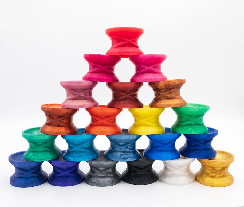 May include: A stack of colorful, double-ended, hourglass-shaped cups, arranged in a pyramid shape. The cups are made of plastic and have a variety of colors, including red, orange, yellow, green, blue, purple, and brown.