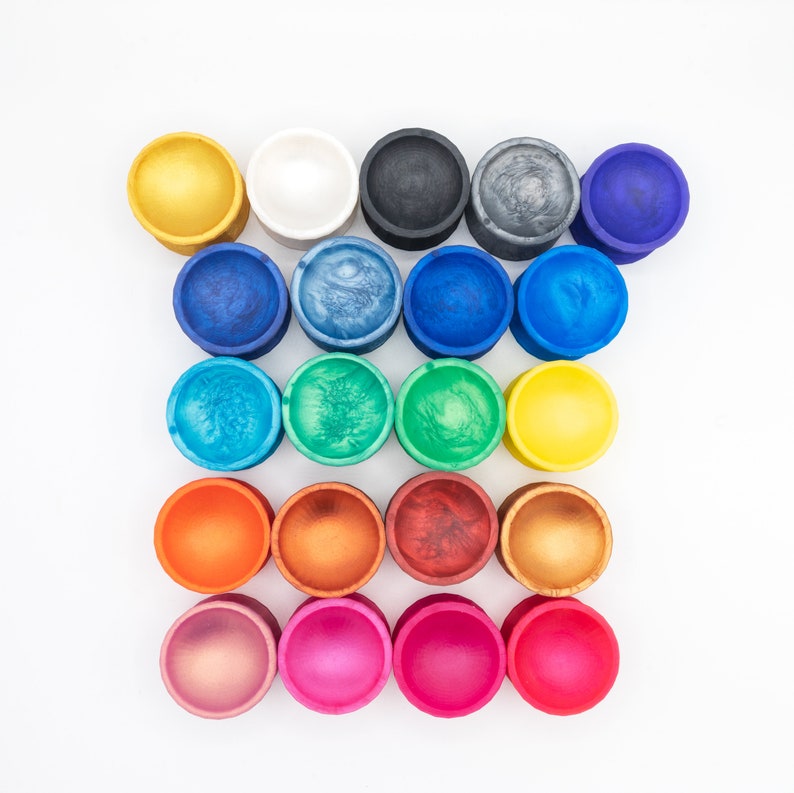 May include: A set of 18 colorful round bowls, arranged in a grid pattern. The bowls are made of a smooth, glossy material and have a variety of colors, including red, orange, yellow, green, blue, purple, and white.