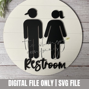May include: A white round sign with black silhouettes of a man and woman, with the text "Restroom" in black lettering.