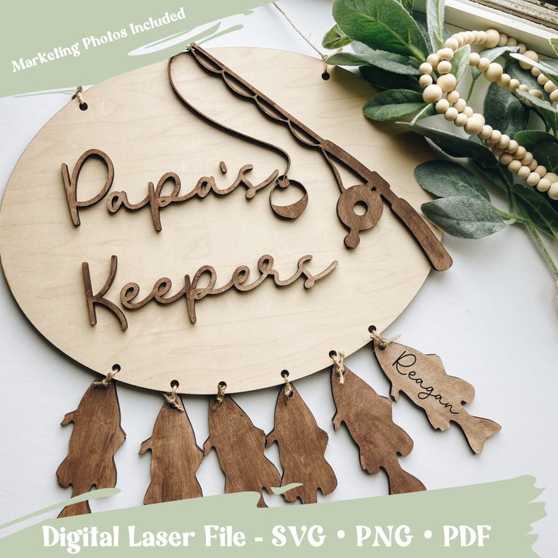 Puede incluir: Un letrero de madera con el texto "Papa's Keepers" y una ca&ntilde;a de pescar con un se&ntilde;uelo. Hay seis peces de madera colgando del letrero, uno de los cuales est&aacute; etiquetado como "Reagan".