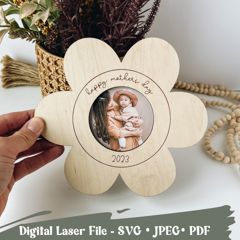 May include: A wooden flower-shaped photo frame with a circular cutout for a photo. The frame is engraved with the text "happy mothers day 2023".
