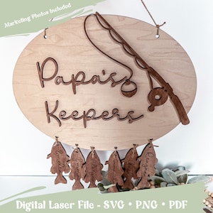 Puede incluir: Un letrero de madera con el texto "Papa's Keepers" y una ca&ntilde;a de pescar con un carrete colgando de &eacute;l. Hay siete peces de madera colgando del letrero, cada uno con un nombre grabado: Emelia, Emma, Adalynn, Samantha, Garl, Reagan.
