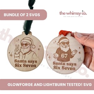 Op de afbeelding: Twee houten kerstversieringen met kerstmanontwerpen. Eén toont de kerstman met een vredesteken, de andere toont de kerstman met het nummer 67. Beide hebben de tekst "Santa says Six Seven".