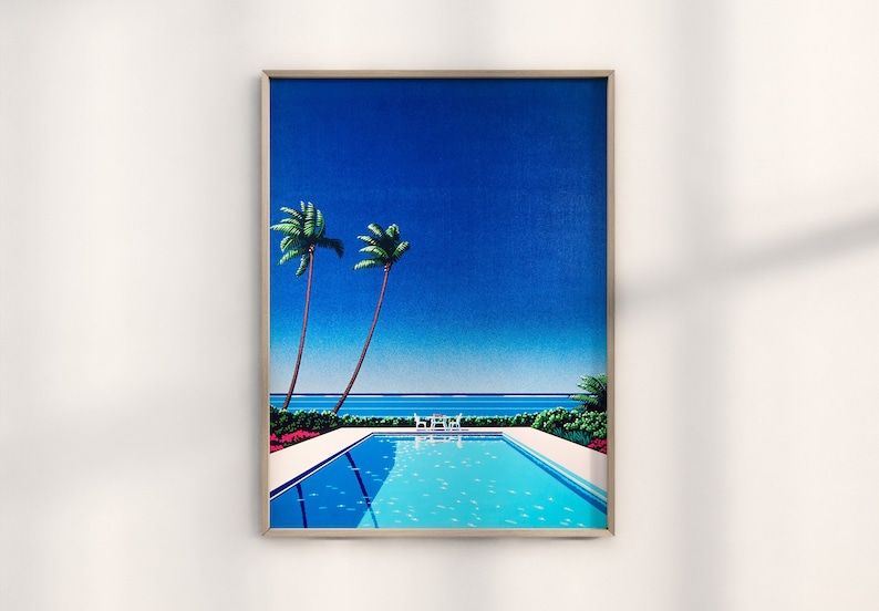 May include: A framed print of a tropical scene with two palm trees, a swimming pool, and a blue ocean in the background. The sky is a bright blue.